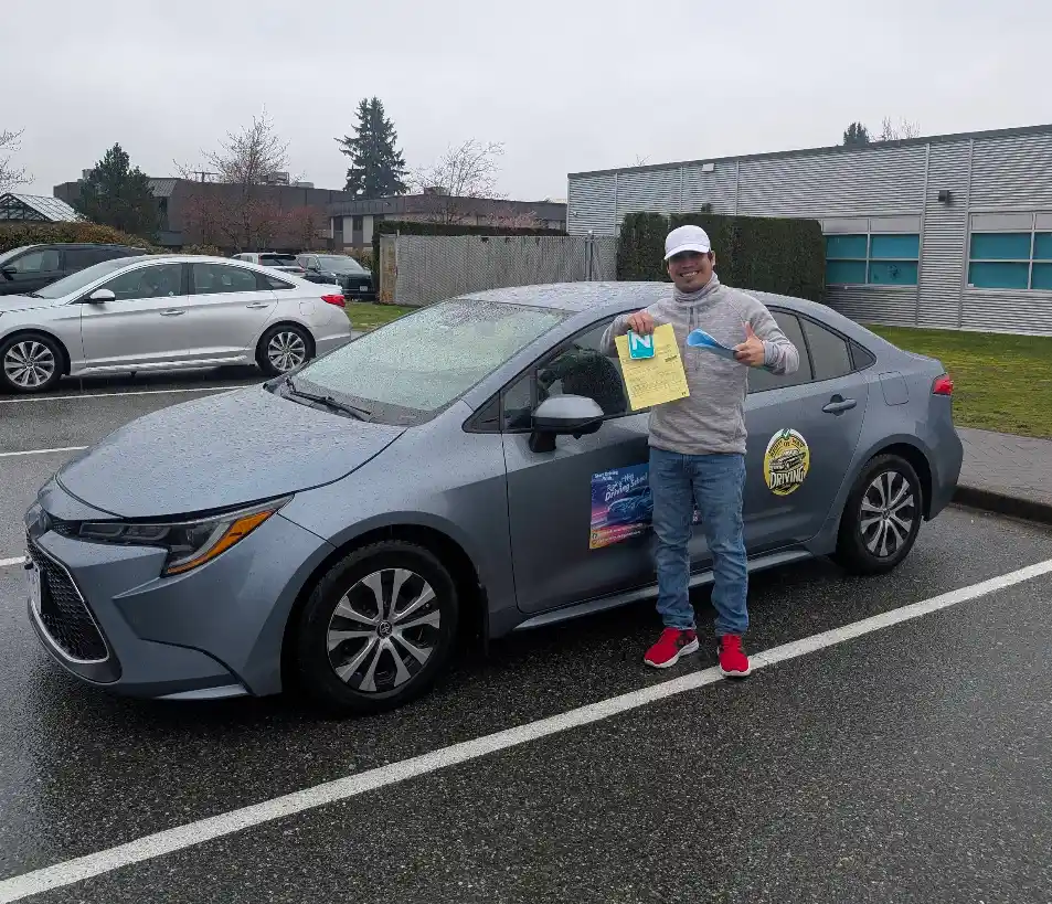 Happy student holding road test paperwork beside the training car