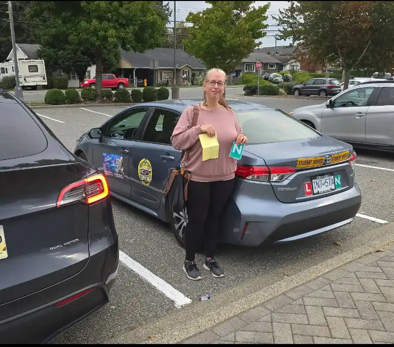 Happy student holding her N sign next to the Right of Way training car