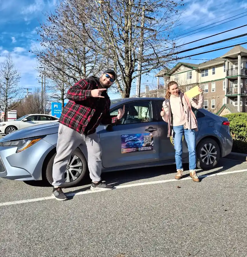 Olya Yakivets celebrating a road test pass beside the Right of Way driving school car